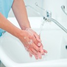 A nurse washes her hands in a sink.