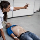 A lady indicates people should stand clear as she administers CPR.