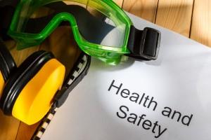 A health and safety hand book with googles and ear protectors on top.