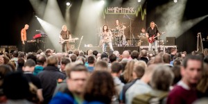 A rock band playing music to a festival crowd.