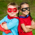 Two young kids dressed as superheroes, smiling.