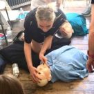 A teenage girls with a first aid mannequin on a first aid for schools course.