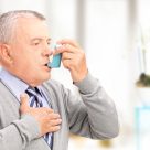 An elderly man using an asthma inhaler.