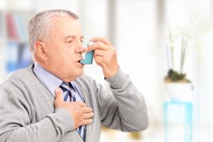 An elderly man using an asthma inhaler.